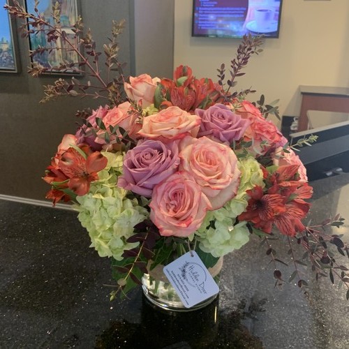 Pink and lavender roses with green hydrangea and alstroemeria in a glass vase featuring Durham luxury flowers