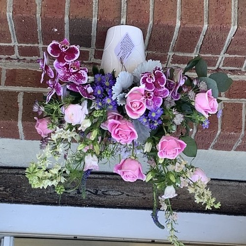 Purple orchids and pink roses with blue ageratum cascading on a brick ledge by a luxury florist Durham