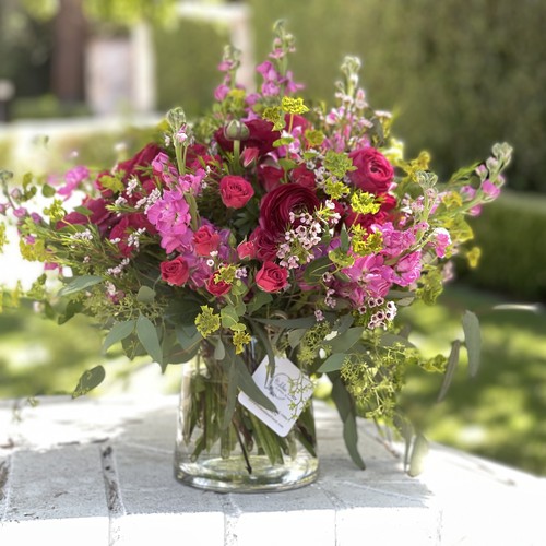 Hot pink roses stock and waxflower in a glass jar in a garden by Durham luxury florist
